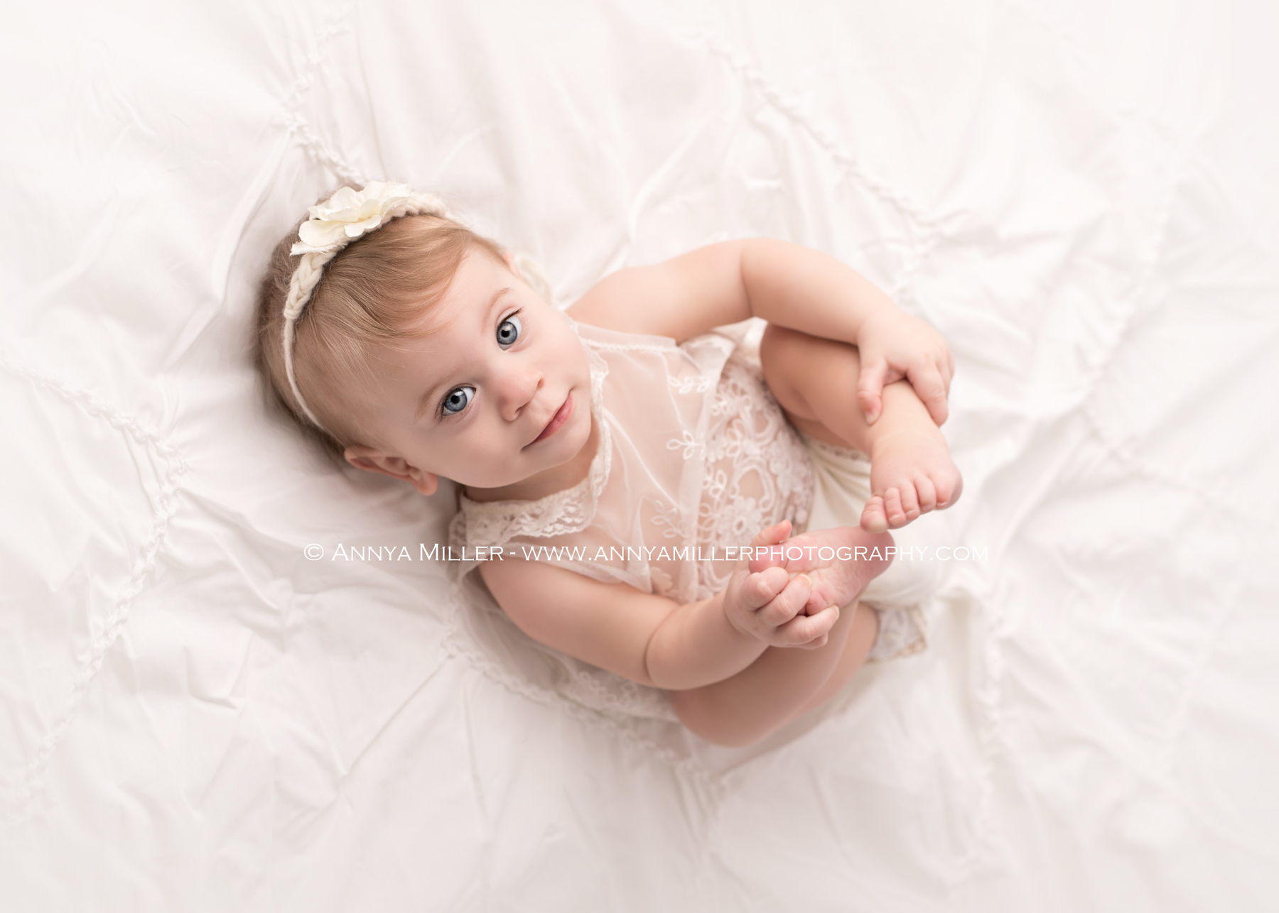 Photograph of baby girl on a white bed by Pickering photographer Annya Miller