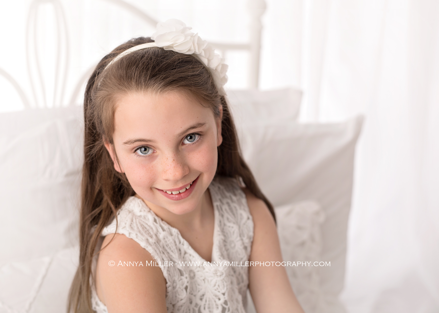 Gorgeous little girl sitting on a white bed by Pickering photographer Annya Miller