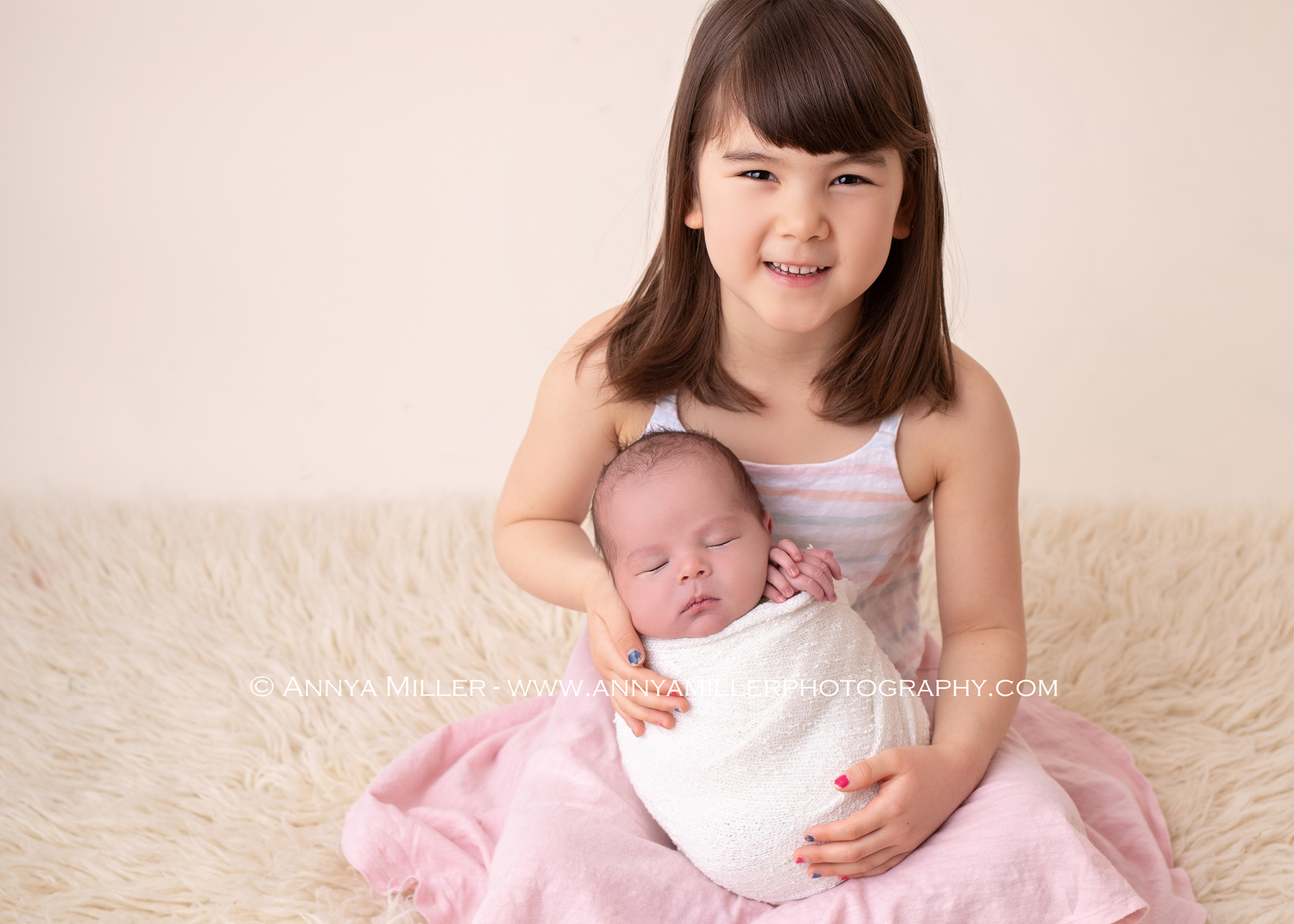 Older sister holding her baby brother in durham newborn photos