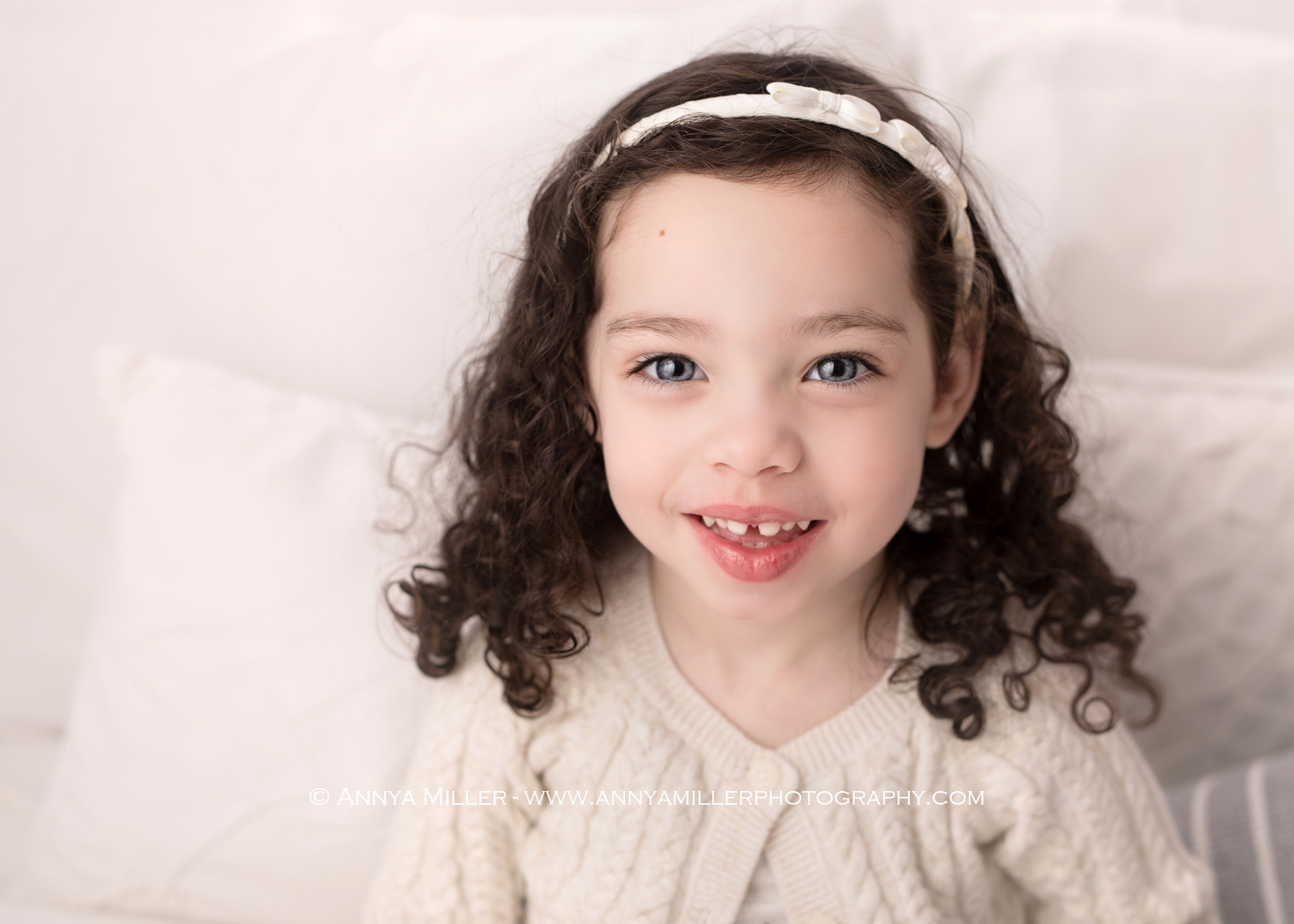 Little girl on white bed by Durham Region maternity photographer Annya Miller 